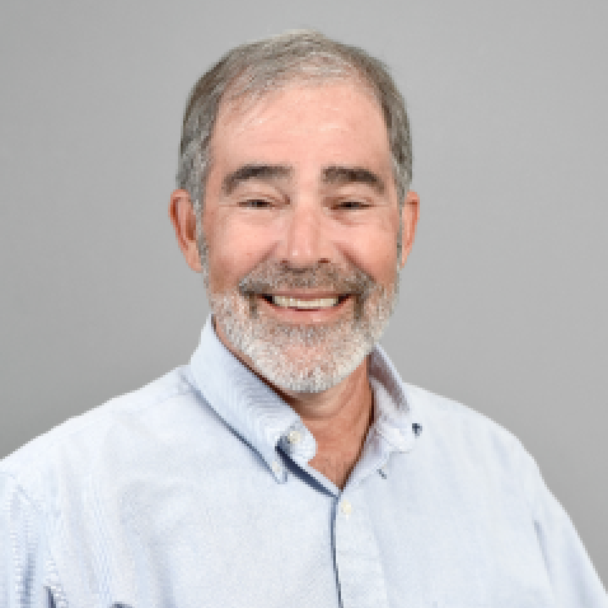 White man with grey hair and a beard smiling